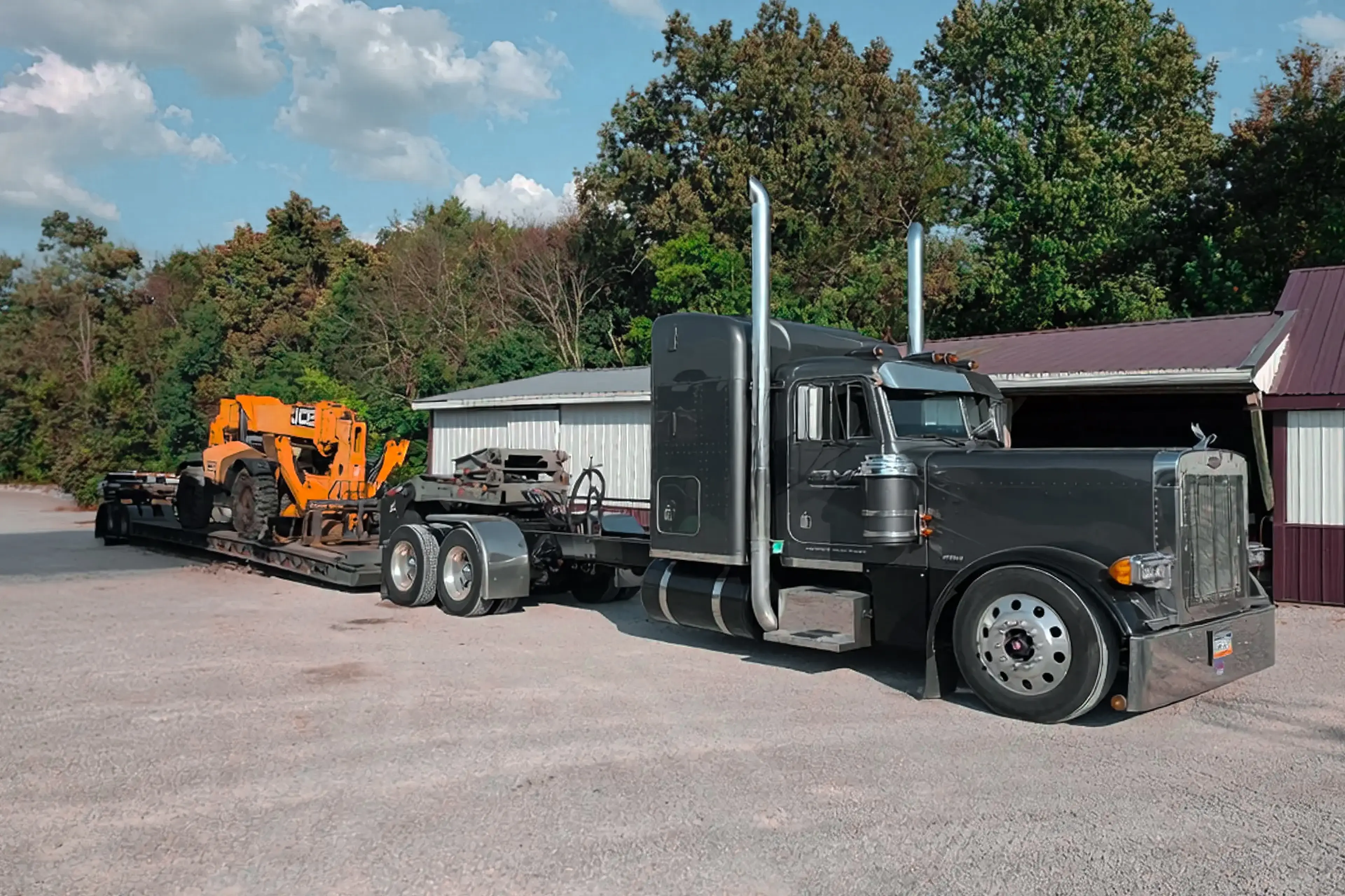 Peterbilt conventional semi-tractor hauling a trailer loaded with a JCB telehandler